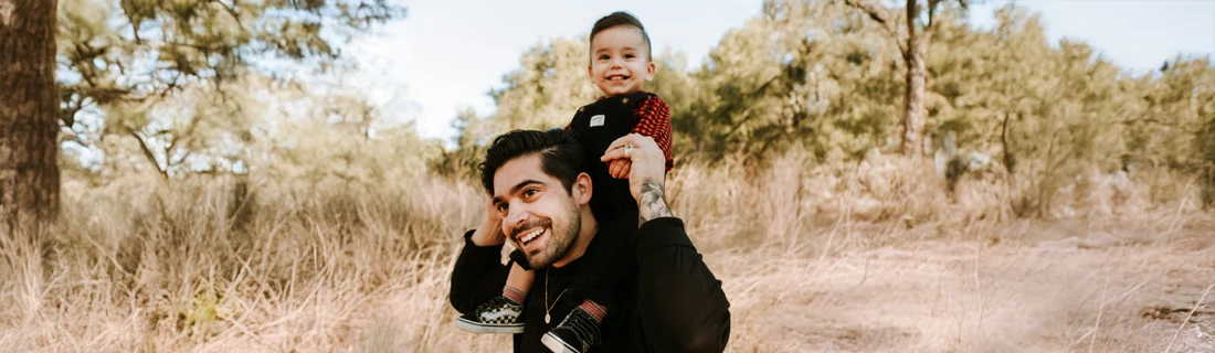 A dad holding his son on his shoulders.