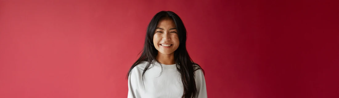 A woman smiling in front of a red wall.